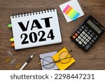 Small photo of vat 2024 text on notepad pages with tacky bookmarks and stickers. calculator and glasses