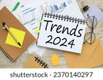 notepad with spring and glasses. bright financial charts. text 2024 trends