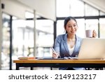 Small photo of Asian Businesswoman Using laptop computer and working at office with calculator document on desk, doing planning analyzing the financial report, business plan investment, finance analysis concept.