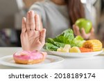 Diet, Dieting young asian woman or girl use hand push out, deny sweet donut and choose green apple, salad vegetables, eat food for good healthy, health when hungry. Close up female weight loss person.