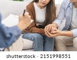Small photo of Psychology, depression asian young couple, patient consulting problem mental health with psychologist, psychiatrist at clinic together, husband encouraging by holding hand of wife, therapy health care
