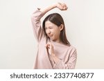 Small photo of Bad smelling, deodorant asian young woman smell stink, breathing nose on armpit with underarm, smelly shirt dirty stinky laundry, disgusting from clothes after washed. Medical health, skin body care.