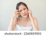 Small photo of Dermatology, scratch asian young woman looking at mirror, expression worry and itch, itchy allergy or allergic sensitive reaction, red spot or rash on her face. Beauty care from skin problem treatment
