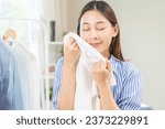 Small photo of Feel softness, hygiene. Smile asian young woman touching fluffy white shirt smelling fresh clean clothes, pretty girl comfort sniff after washing laundry. Household work at home, chore of maid concept