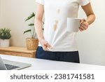Small photo of Cloth stain, disappointment asian young woman, girl clumsy with hot coffee, tea stains, hand show making spill drop on white t-shirt, spot dirty or smudge on clothes while working on computer at home.