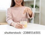 Small photo of Smile asian young woman putting or dropping effervescent tablet into glass of water, holding pain pill, painkiller medicine, aspirin for treatment, take vitamin c for hangover. Health care concept.