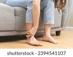 Small photo of Foot pain concept, close up hand of young woman rubbing, massaging sore feet area of pain, girl suffering on sofa, couch at home. Discomfort painful feet ache from walking for long. Physical injury.