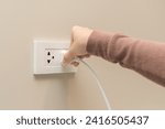 Small photo of Hand of woman plugged in, unplugged electricity cord cable at home, put on or remove electric plug cable in socket on wall outlet for saving, control power electrical energy, eco environment concept.