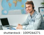Small photo of Young male travel agent consultant in tour agency wearing headset
