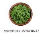 Chopped fresh parsley leaves in a wooden bowl, isolated on white background, top view