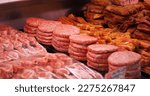 Small photo of Raw minced meat beef burger cutlets in a window shop. Beef burgers and other meat preps ready to be sold. Food industry.