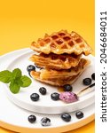 Small photo of Stack of Croissant Waffle or Croffle with mint leaves and blueberry topping served in white plate. Selective focus image. Viral snacks in Indonesia nowadays.