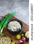Small photo of Ikan Teri Basah or fresh anchovies on black ceramic bowl with some raw ingredients. Indonesian fish from sea.