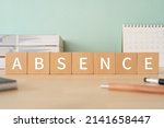 Small photo of Wooden blocks with "ABSENCE" text of concept, pens, notebooks, and books.