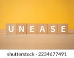 Small photo of Wooden blocks with "UNEASE" text of concept.