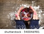 Female hands holding mug with mulled wine above wooden table. Top view 