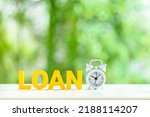 Small photo of Term loan for small business, financial concept : Alpabet letters, the word LOAN, a white alarm clock on a table, green bokeh background. Term loan provides borrowers with a lump sum of cash upfront.
