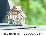 Small photo of Online home auction, online property valuation and tax payment, financial concept : Model half-timbered house on a laptop computer keyboard, depicting a quick online real estate valuation estimate.