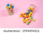 Multicolored chocolate candies scattered in two glass on pink background.Top view of creative colorful sweets background concept with copy space for text.