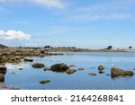 Blue sky and calm sea, Breton shore at low tide. View of a portion of shoreline in Brittany at a place called Saint Michèl France June 2022.