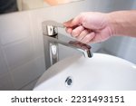 Male hand closing water tap or faucet in bathroom. Save water at home or water conservation concepts