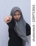 Small photo of Close up young asian muslim woman wear hijab with cranky or angry with finger point on camera gesture isolated on plain white background.