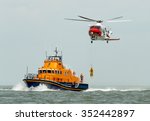 orange sea rescue boat at sea off south coast of Britain man being winched to emergency rescue helicopter