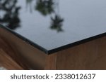 Small photo of A black toughen glass table reflecting a tree's image