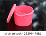 Small photo of A red food container with lid placed on a toughen black glass table