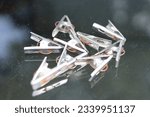 Small photo of Bunch of silver shiny cloth pegs on a black toughen table made of glass