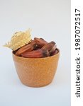 Small photo of Pine nuts in a bowl with straw hat, typical of "festas juninas" on a white background. Typical araucaria seeds, traditional winter brazilian food. Creative concept. Pinion Brazil.