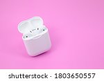Wireless bluetooth headphones and charging case on pink background