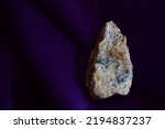 Small photo of Rough beryl on dark purple background, a closeup of yellow white blue mineral on day light, a macro shot.A closeup of natural rock isolated on purple background.Geology, mineralogy.