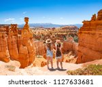 Girls on vacation hiking trip. Friends standing next to Thor's Hammer hoodoo on top of  mountain looking at beautiful view. Bryce Canyon National Park, Utah, USA