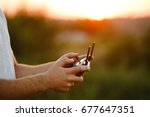 Man holds a drone remote controller in his hands. Close-up of quadrocopter RC during flight. Pilot takes aerial photos and videos with quad on sunset