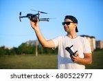 Happy smiling man holds small compact drone and remote controller in his hands. Pilot launches quad copter from his palm. Drone ready to launch