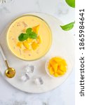 Small photo of A bowl of Mango sago, Hongkong dessert made from mango juice, jelly, sago pearl, evaporated milk and sweetened condensed milk. Top view, white background, Selective focus