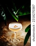 Small photo of Glass of Pisco Sour surrounded by plants