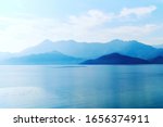 Tranquil landscape of mountains and lake water in the sunrise lights. Morning fog over the water surface. Skadar lake, Montenegro. Nature background