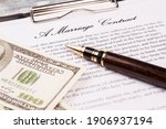 Small photo of Close-up pen with marriage contract and dollars. Signification of marriage contract for money. Mock marriage concept.