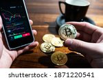 Smartphone with Bitcoin trading chart on the screen. Holding in hand a gold Bitcoin Cash coin. Trading on the cryptocurrency exchange.