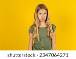 Small photo of Displeased upset beautiful caucasian kid girl wearing green T-shirt frowns face as going to cry, being discontent and unhappy as can't achieve goals, Disappointed model has troubles