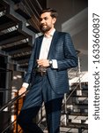 Small photo of Young businessperson with eyeglasses in his hand standing on the stairs