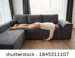 Lonely man. Sad thoughtful handsome man lying in the empty room on the sofa face down on the stomach and suffering. Stock photo