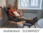 Male reader taking nap at comfortable armchair at home during the evening