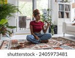 Small photo of Gracious young woman holding santa palo wood and doing meditation in cozy room