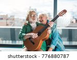 Small photo of Musical holiday. Waist up portrait of amorous married man and woman enjoying playing on instrument