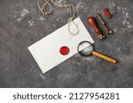 Blank retro stationery. Vintage envelope with wax seal, stamp, magnifier, spoon and rope on concrete background. Flat lay.