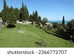 Small photo of NEW ATHOS, REPUBLIC OF ABKHAZIA - JULY 29, 2023: Trees and buildings on a green slope in the Park of the New Athos monastery against the blue sky and the Black sea.