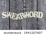 Small photo of Swearword - concept design template on rustic wooden background with wavy line of alphabet letters and copyspace above and below